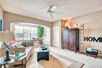 A living room with a couch, a coffee table, and a ceiling fan.